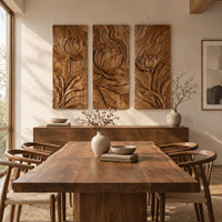 Set of three tall wooden panels carved with lotus flowers in relief beside a dining table in natural light