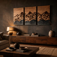 Three panel wood wall art with a carved mountain range above dark waves above a low console in an evening living room