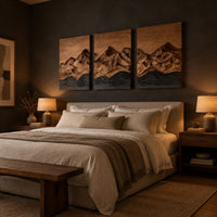 Three panel wood wall art with a carved mountain range above dark waves above a bed in a dusk lit bedroom