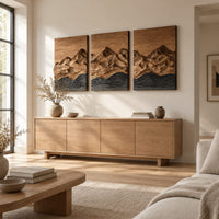 Three panel wood wall art with a carved mountain range above dark waves above a light oak sideboard in daylight
