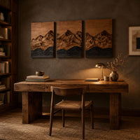 Three panel wood wall art with a carved mountain range above dark waves above a desk in a dark study corner