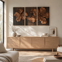 Three panel carved floral relief wall art with large petals on dark panels above a light oak sideboard in daylight