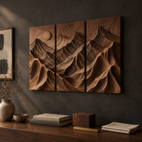 Detail of three panel carved mountain relief wall art with a sun disc beside wood, brass and linen samples