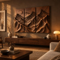 Three panel carved mountain relief wall art with a sun disc above a low console in an evening living room