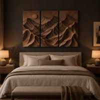 Three panel carved mountain relief wall art with a sun disc above a bed in a dusk lit bedroom