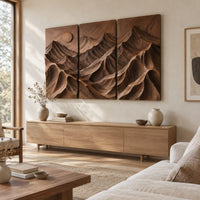 Three panel carved mountain relief wall art with a sun disc above a light oak sideboard in daylight