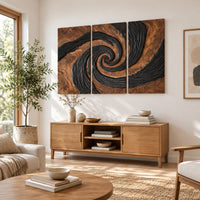 Three panel spiral wall art with a carved black swirl on warm wood in a bright sunroom with green plants