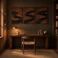 Set of three framed wood panels carved with a dark winding river above a desk in a dark study corner