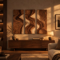 Three panel wall art with flowing bands of dark and light wood grain above a low console in an evening living room