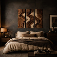Three panel wall art with flowing bands of dark and light wood grain above a bed in a dusk lit bedroom