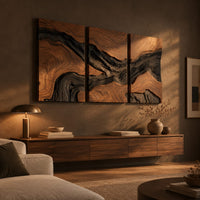 Three panel wood grain wall art with a dark flowing river band above a low console in an evening living room