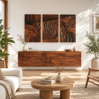 Three panel wall art with flowing carved grain pattern in a bright sunroom with green plants