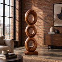 Stacked three ring sculpture with open centers on a flat plinth in an industrial loft living room with exposed brick