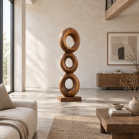 Stacked three ring sculpture with open centers on a flat plinth in a bright open plan living room