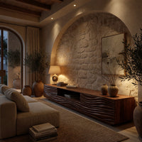 Media cabinet with wave carved doors around an open niche in an evening room lit by two lamps