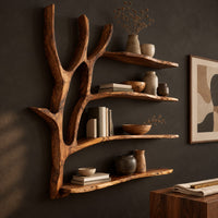 Corner detail of tree branch wall shelf with four boards and a forked trunk beside wood, brass and linen samples
