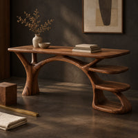 Corner detail of wooden desk shaped like a tree with branching legs and two open shelves beside wood, brass and linen samples