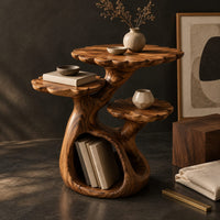 Corner detail of tree shaped side table with three petal edged tops and a hollow trunk beside wood, brass and linen samples