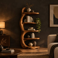 Tree trunk bookshelf with five tiered shelves branching from a twisting stem in a dark living room at golden hour