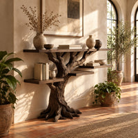Console table shaped like a tree with root feet and staggered shelves in a bright entryway with arched windows and plants