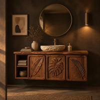 Bathroom vanity cabinet with three tropical leaf carved doors and an open shelf in a dark bathroom at golden hour