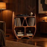 Turntable stand shaped like a sculpted open shelf unit with two pointed tips in an evening living room with walnut wall paneling
