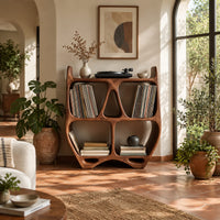 Turntable stand shaped like a sculpted open shelf unit with two pointed tips in a bright living room with arched windows and plants