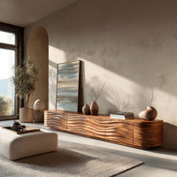 Low TV stand with wave carved door fronts in an open plan space in daylight
