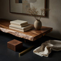 Corner detail of split level live edge TV stand on tapered legs beside wood, brass and linen samples