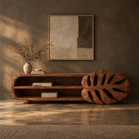 Corner detail of low tv stand with two open shelves and a carved monstera leaf end beside wood, brass and linen samples