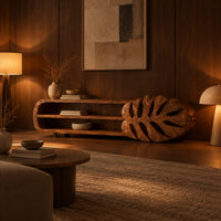 Low tv stand with two open shelves and a carved monstera leaf end in an evening living room with walnut wall paneling