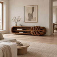 Low tv stand with two open shelves and a carved monstera leaf end in a Scandinavian living room with white walls