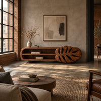 Low tv stand with two open shelves and a carved monstera leaf end in an industrial loft living room with exposed brick