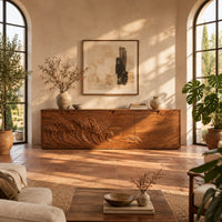 Low wooden tv stand with carved ocean wave and sun ray doors in a bright living room with arched windows and plants