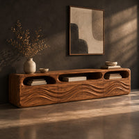 Low tv stand with carved wave relief on the front and open top cubbies, three-quarter view showing the grain
