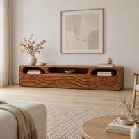 Low tv stand with carved wave relief on the front and open top cubbies in a Scandinavian living room with white walls