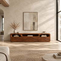 Low tv stand with carved wave relief on the front and open top cubbies in a bright open plan living room