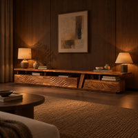 Long low tv stand with carved wave fronts and an open shelf above in an evening living room with walnut wall paneling