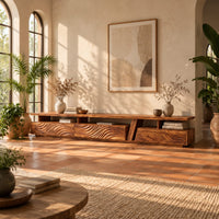 Long low tv stand with carved wave fronts and an open shelf above in a bright living room with arched windows and plants
