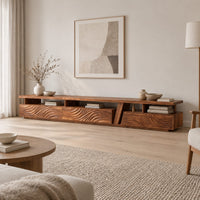 Long low tv stand with carved wave fronts and an open shelf above in a Scandinavian living room with white walls