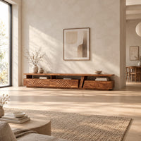 Long low tv stand with carved wave fronts and an open shelf above in a bright open plan living room