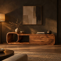 Low tv stand with curled scroll end and two drawers in a dark living room at golden hour