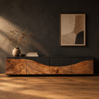 Low tv stand with carved flowing grain panels under a dark top band in a dark studio against a charcoal plaster wall