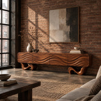 Tv stand with four wave carved panels on two twisting ribbon feet in an industrial loft living room with exposed brick