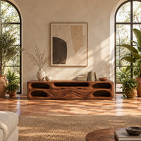 Long tv stand with pill shaped end niches and two center fronts in a bright living room with arched windows and plants