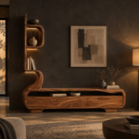 Low media console with a tall sculpted display tower at one end in a dark living room at golden hour