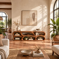 Low wooden tv stand with two rows of sculpted open cells in a bright living room with arched windows and plants