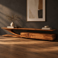 Corner detail of tv stand with a sweeping plank top and a low two panel cabinet block beside wood, brass and linen samples
