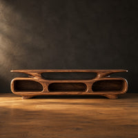 Low tv stand with three open oval cubbies under a sculpted slab top in a dark studio against a charcoal plaster wall