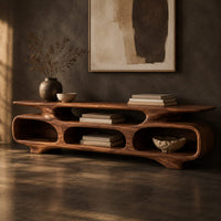 Corner detail of low tv stand with three open oval cubbies under a sculpted slab top beside wood, brass and linen samples